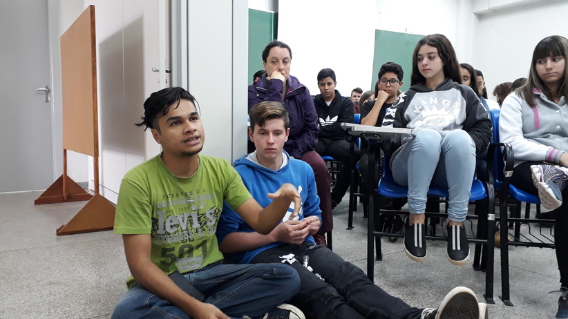 Estudante sentado ao chão fazendo pergunta aos palestrantes em evento de combate à homofobia no ambiente escolar