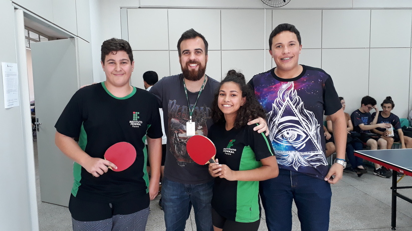 Estudantes atletas e técnico do Campus Avançado Astorga posando para foto segurando raquete vermelha durante a fase macrorregional na modalidade tenis de mesa dos Jogos Escolares do Paraná 2019
