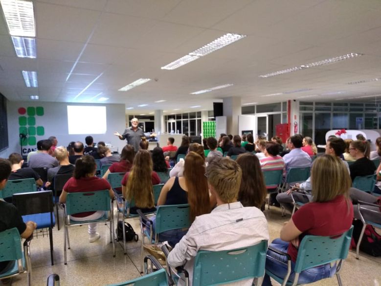 No auditório do Campus Capanema, o público assiste ao professor Valdeni proferir uma fala sobre a importância da matemática no cotidiano.