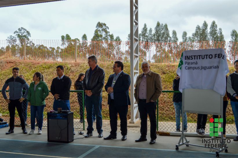 Autoridades locais e do IFPR posicionadas, em pé, ao lado na placa que registra a inauguração da quadra coberta do Campus Jaguariaíva