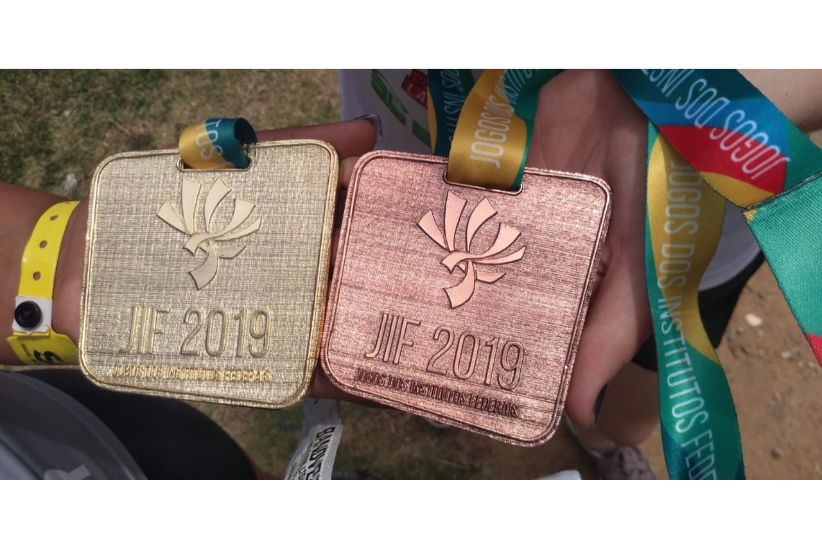 Duas medalhas lado a lado, uma de ouro e outra de bronze. Em cada uma delas,, gravada, a marca do JIF 2019