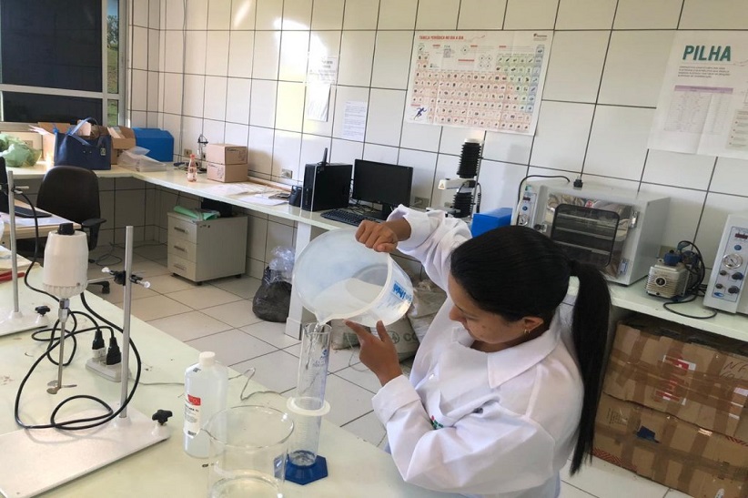 "Ambiente de laboratório. Uma mulher segura materiais para produção de álcool em gel"