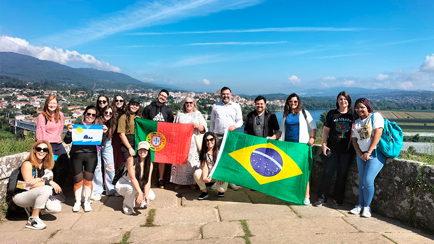 Alunos e servidores seguram bandeiras do Brasil e de Portugal, e posam para foto